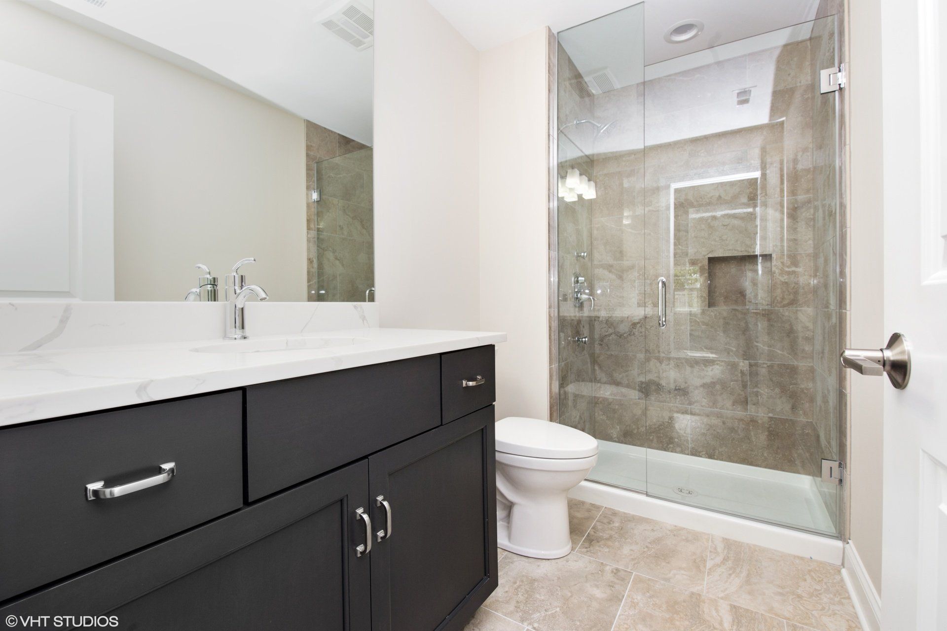 A bathroom with a toilet , sink , mirror and walk in shower.