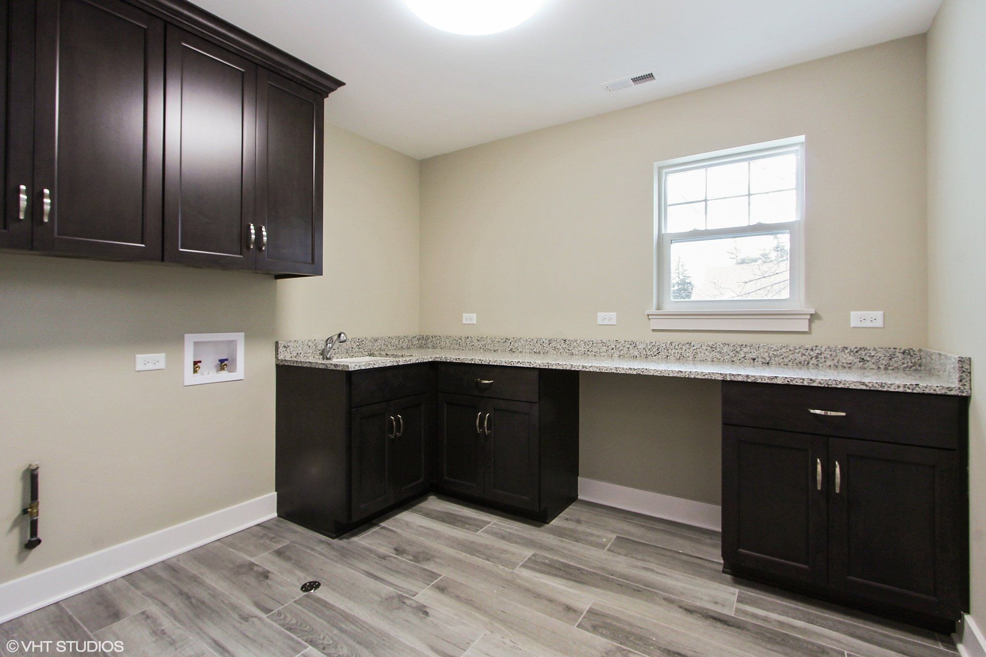 A laundry room with black cabinets and a window