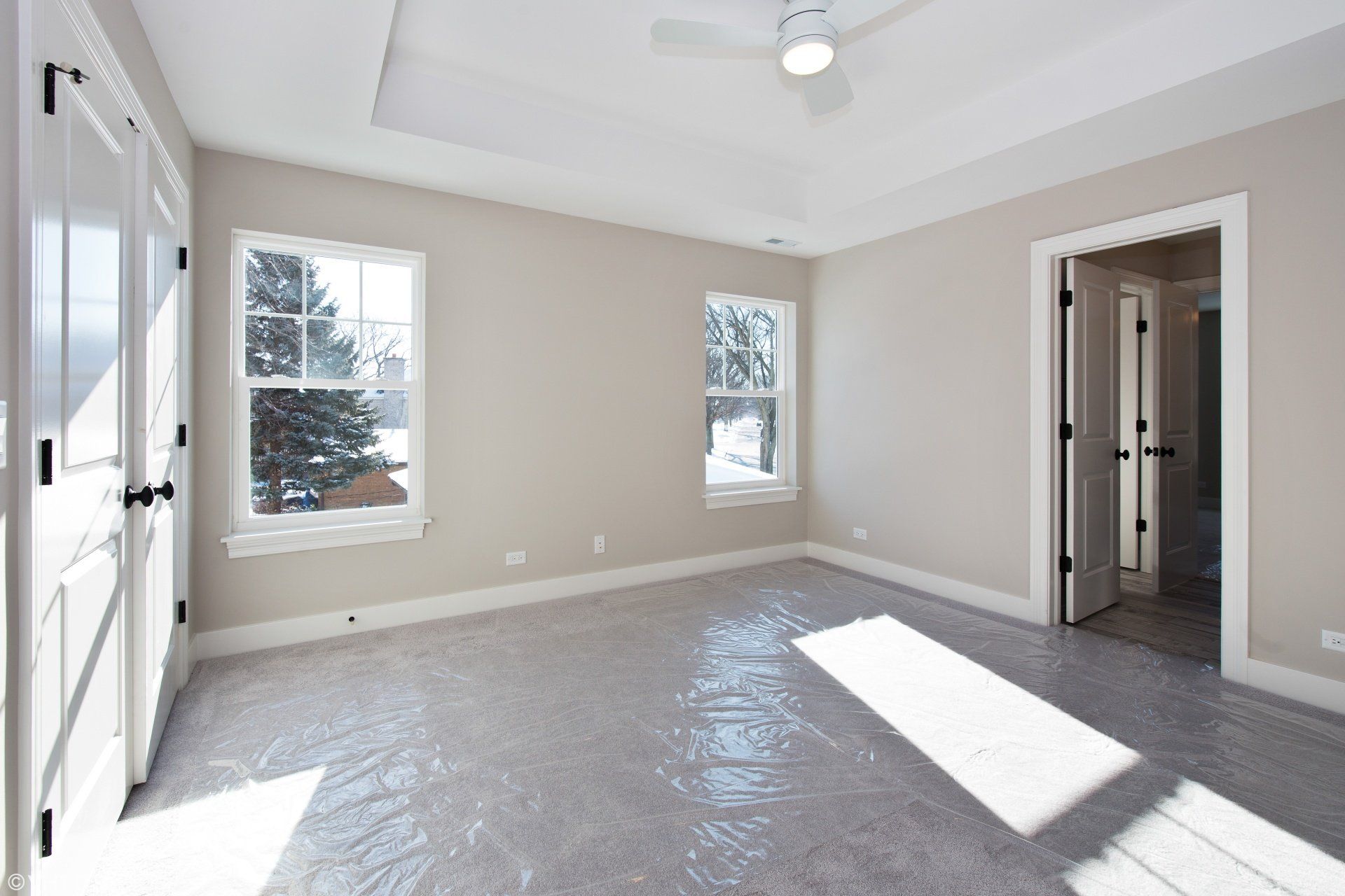 An empty bedroom with a ceiling fan and two windows