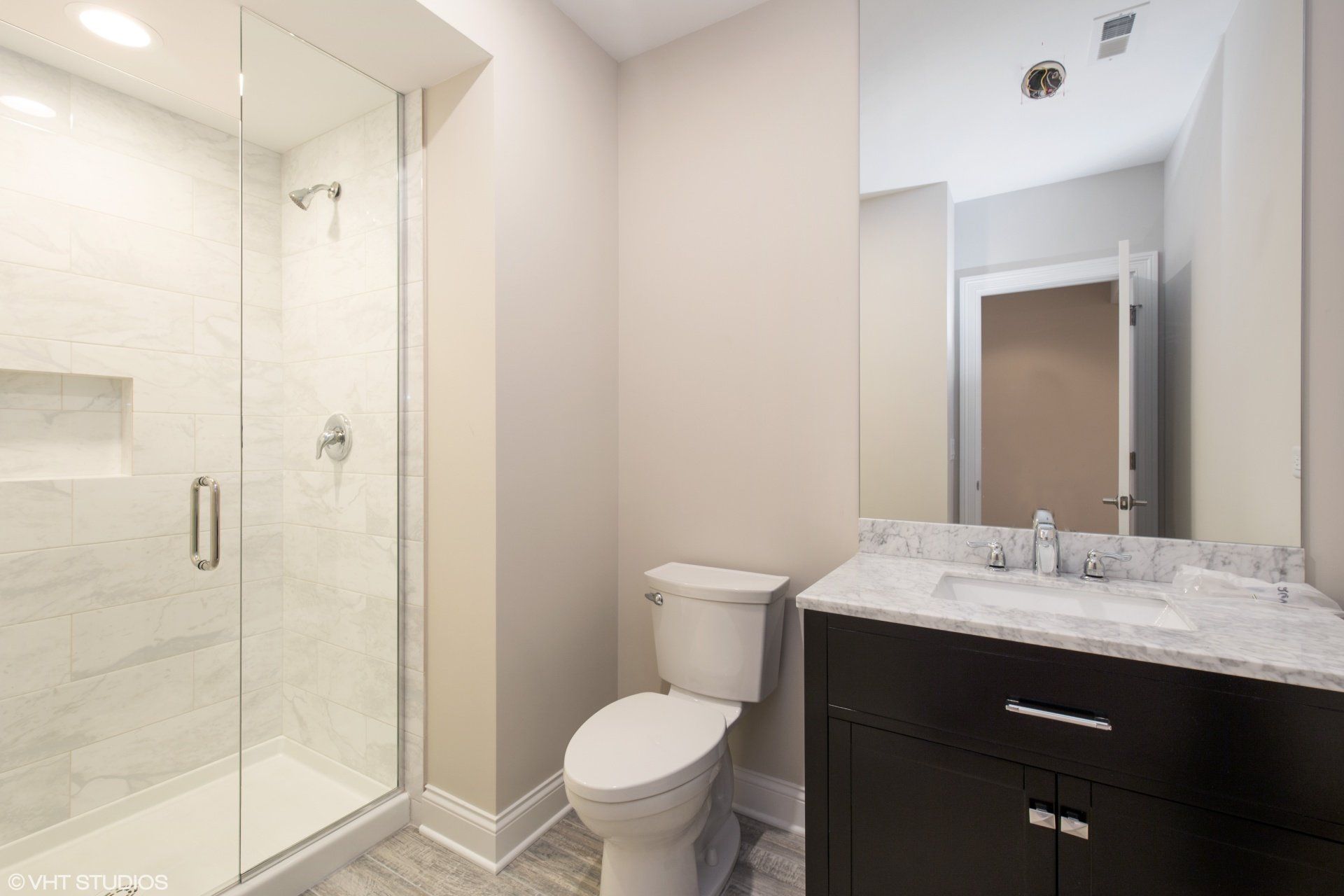 A bathroom with a toilet , sink , shower and mirror.
