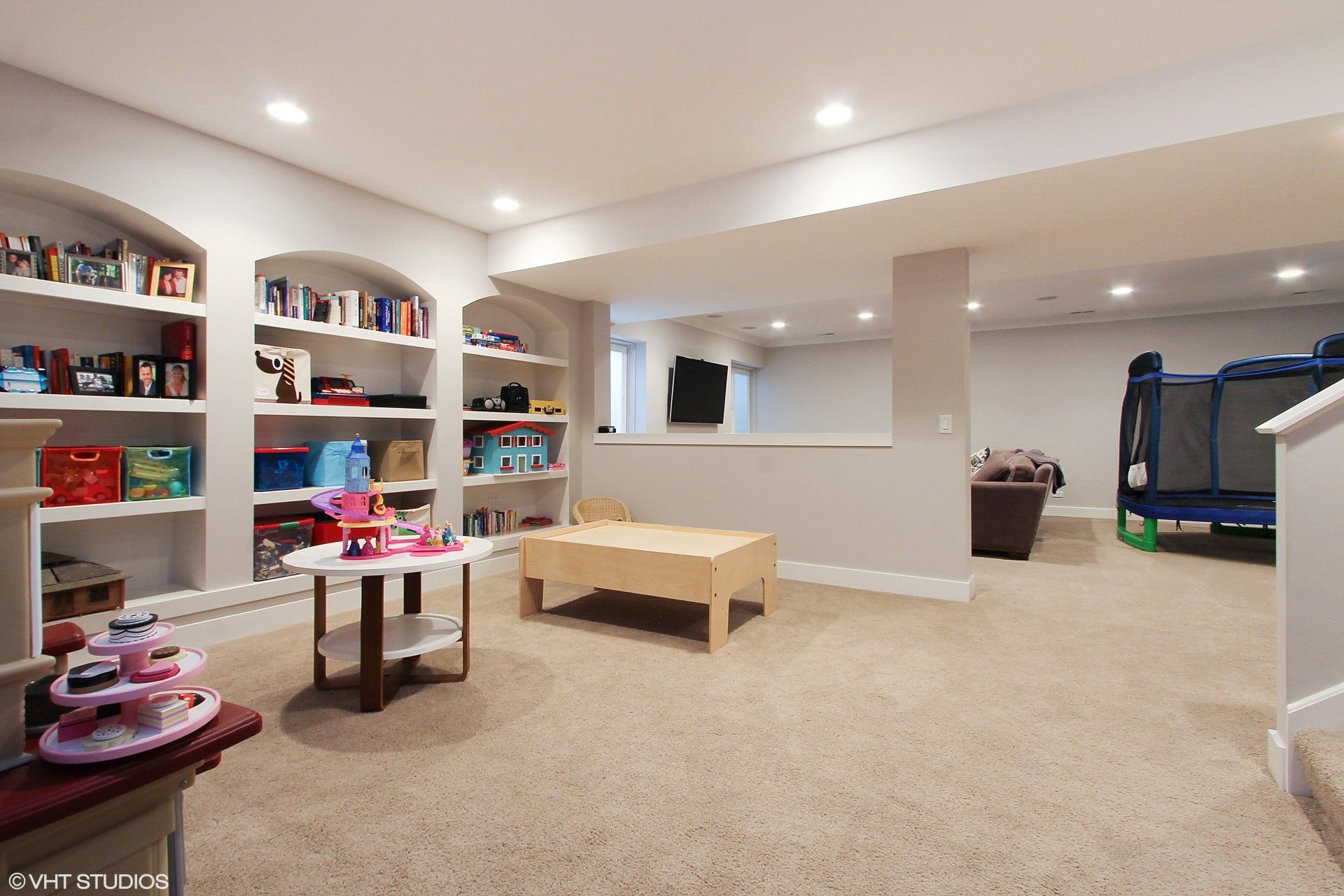 A basement with a table and shelves filled with toys
