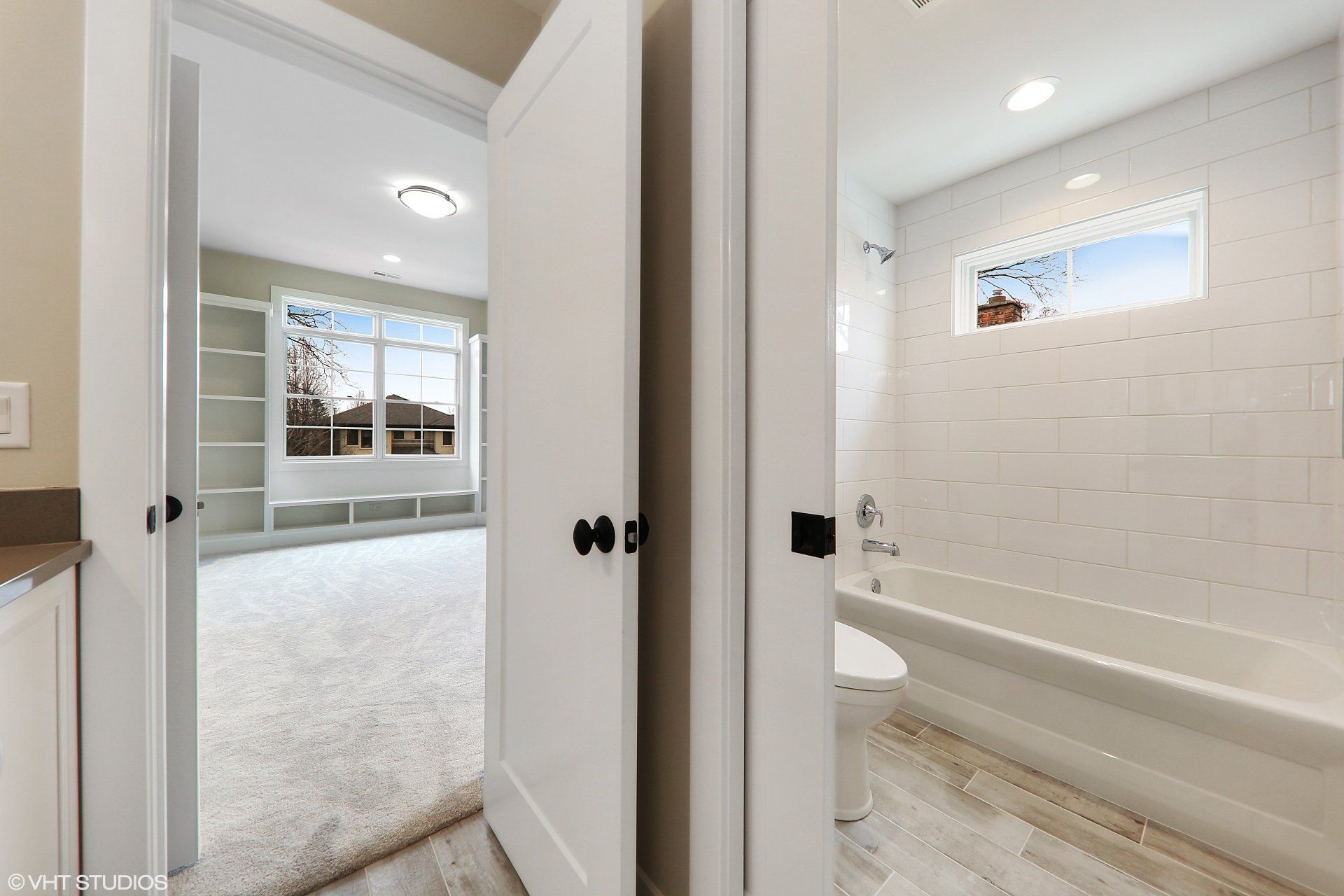 A bathroom with a tub , toilet , and window.