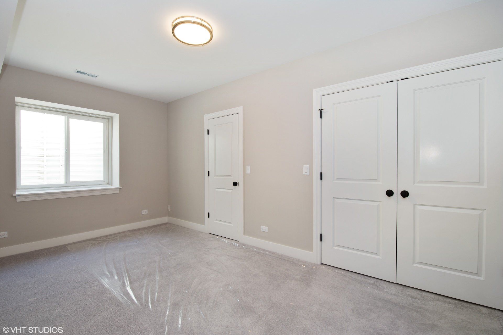 An empty room with two white doors and a window