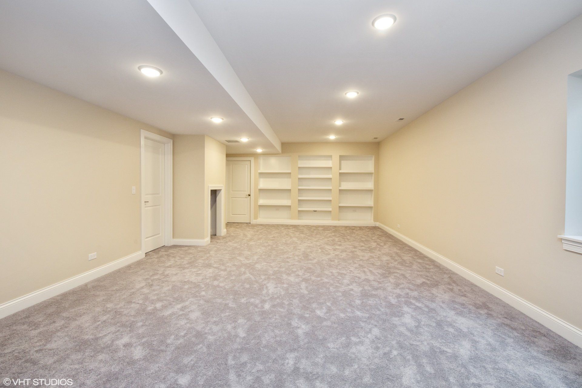 An empty basement with a carpeted floor and shelves.