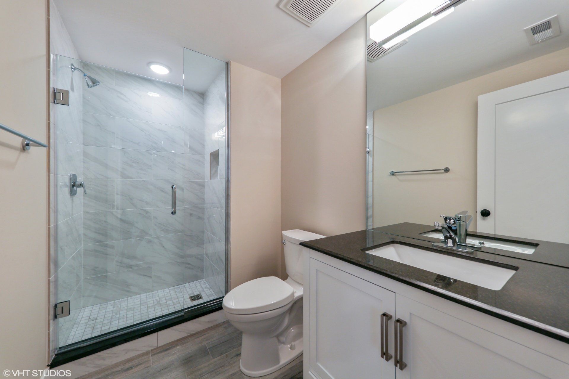 A bathroom with a toilet , sink and shower.