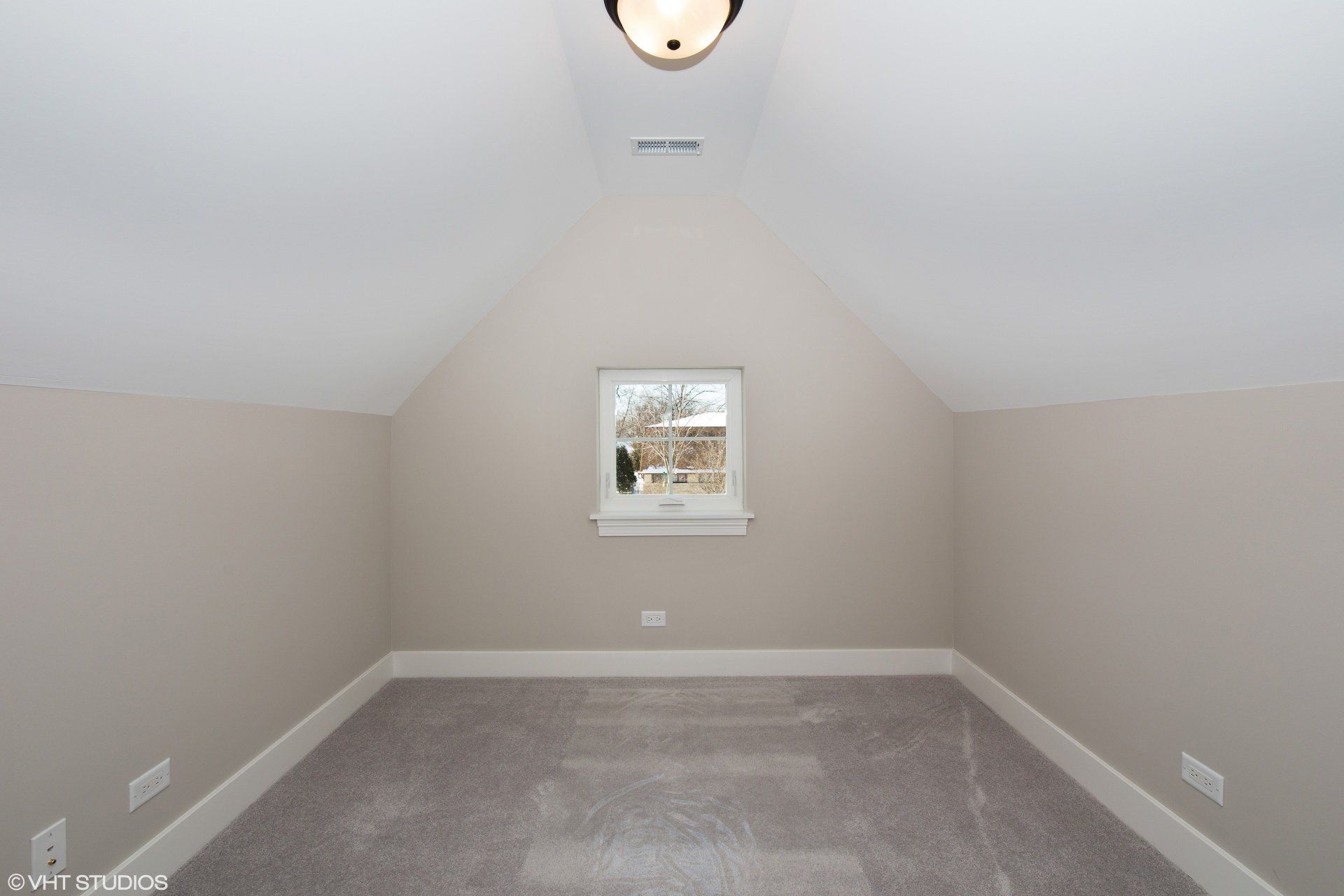 An empty room with a vaulted ceiling and a window