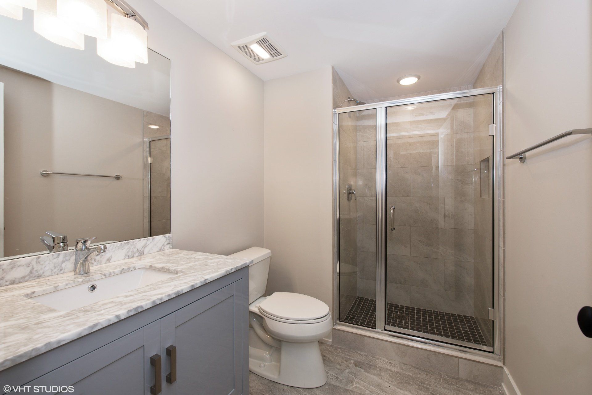 A bathroom with a toilet , sink and shower.
