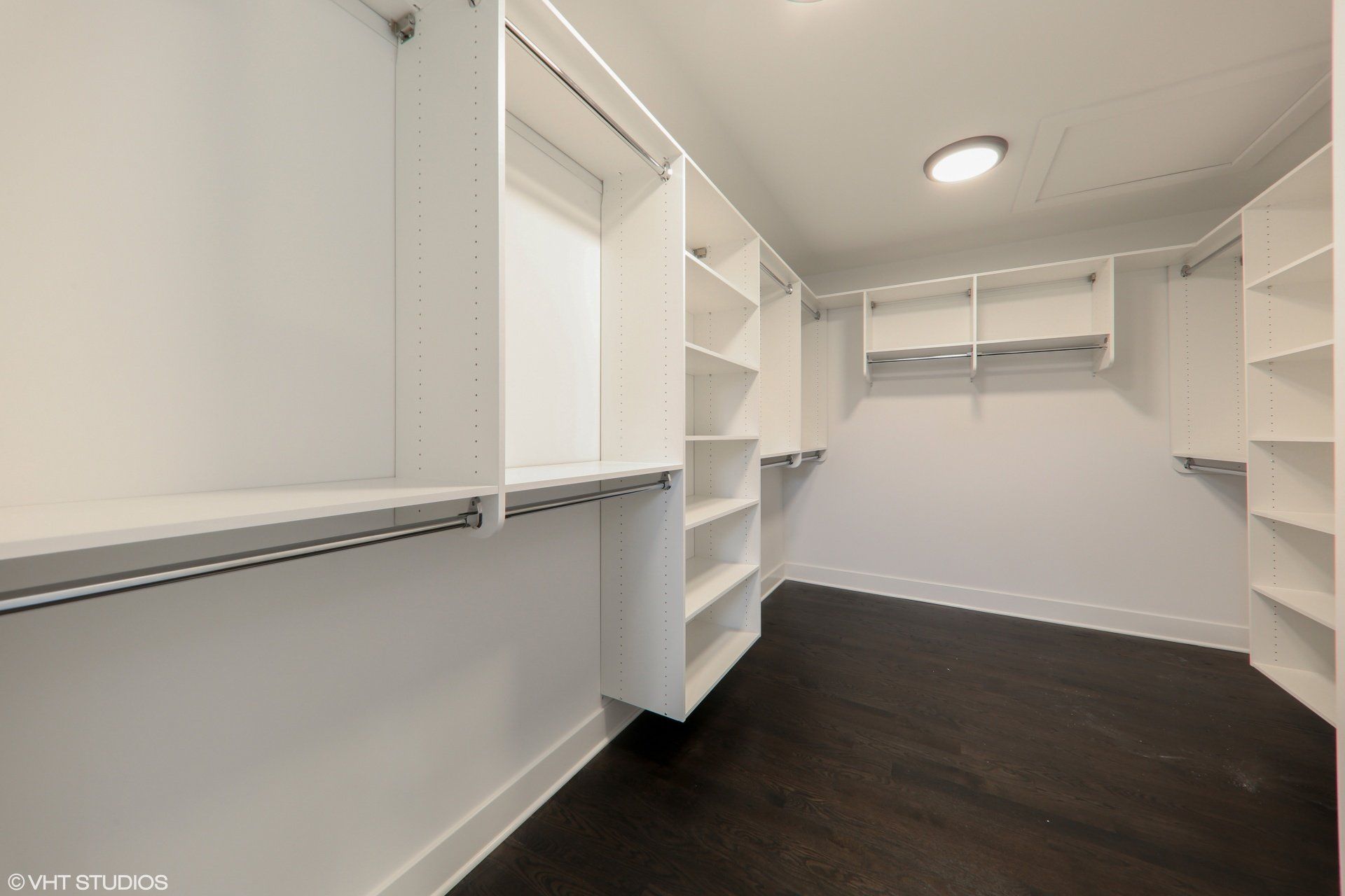 A walk in closet with lots of shelves and clothes racks.
