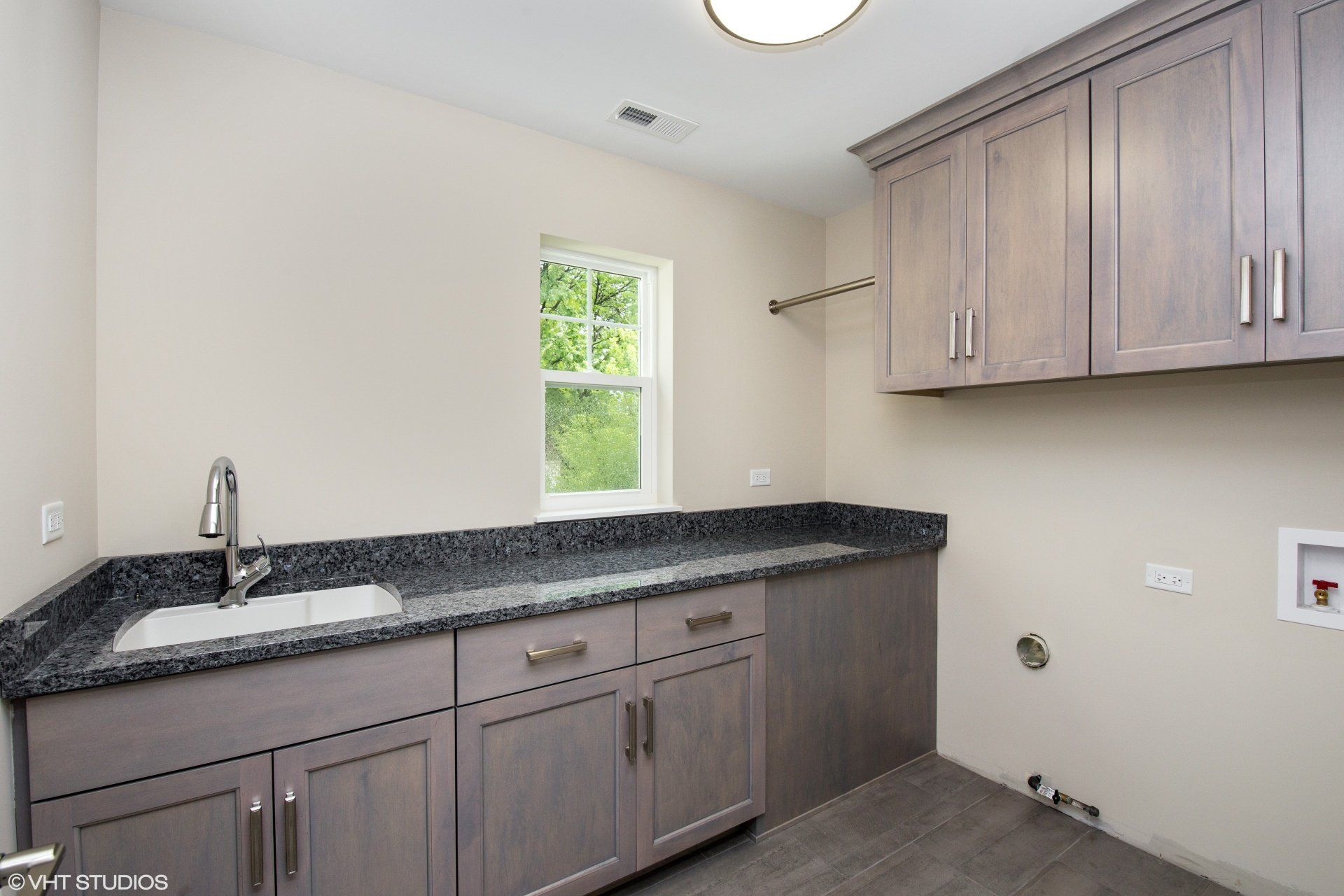 A laundry room with a sink and cabinets and a window