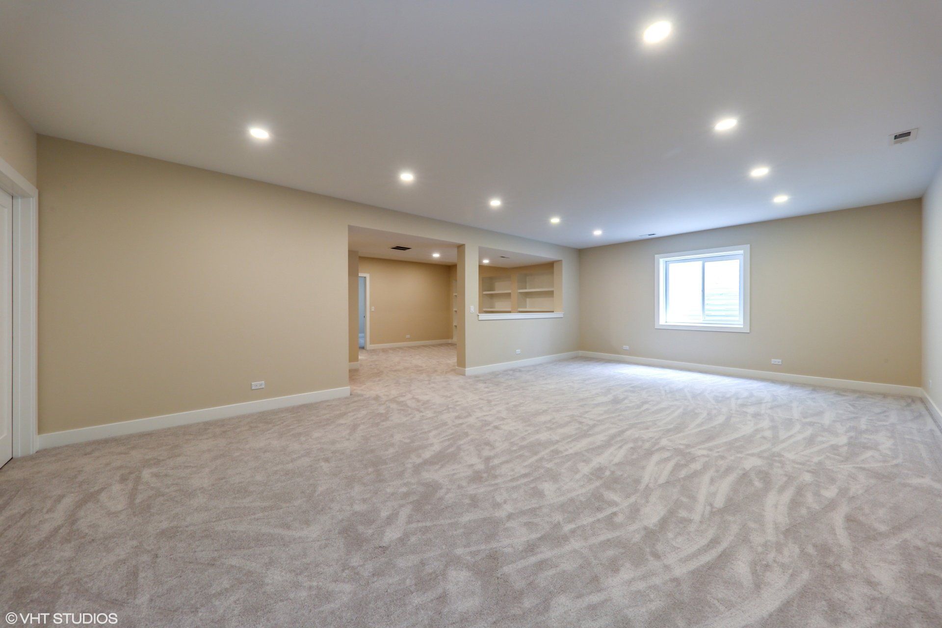An empty basement with a carpeted floor and a window