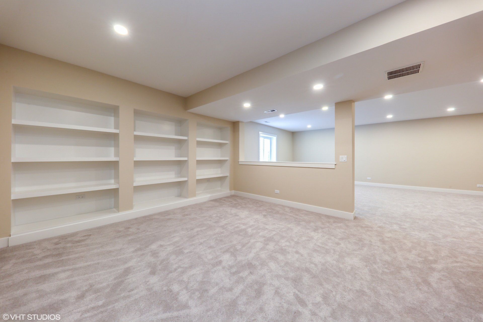 An empty basement with a lot of shelves and carpet.