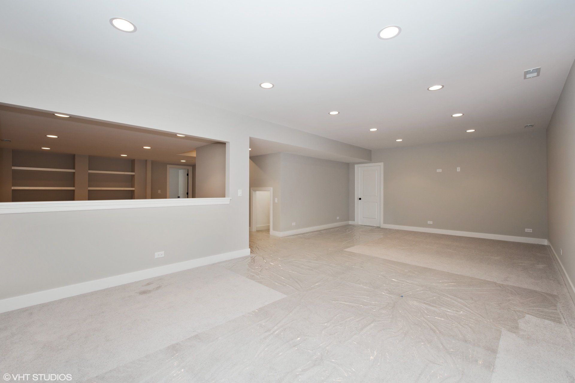 An empty basement with a large window and a staircase.