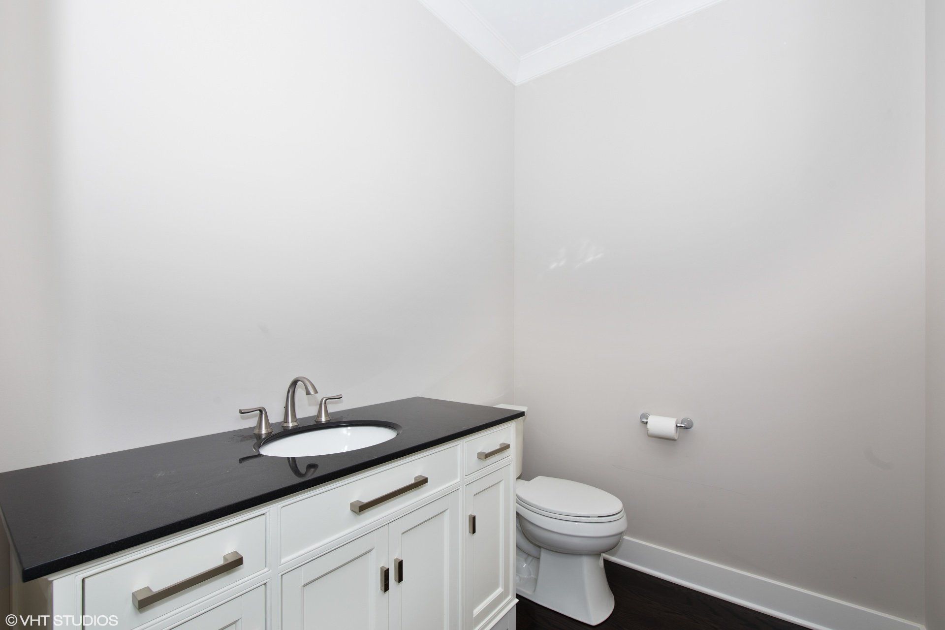 A bathroom with a sink , toilet and black counter top.