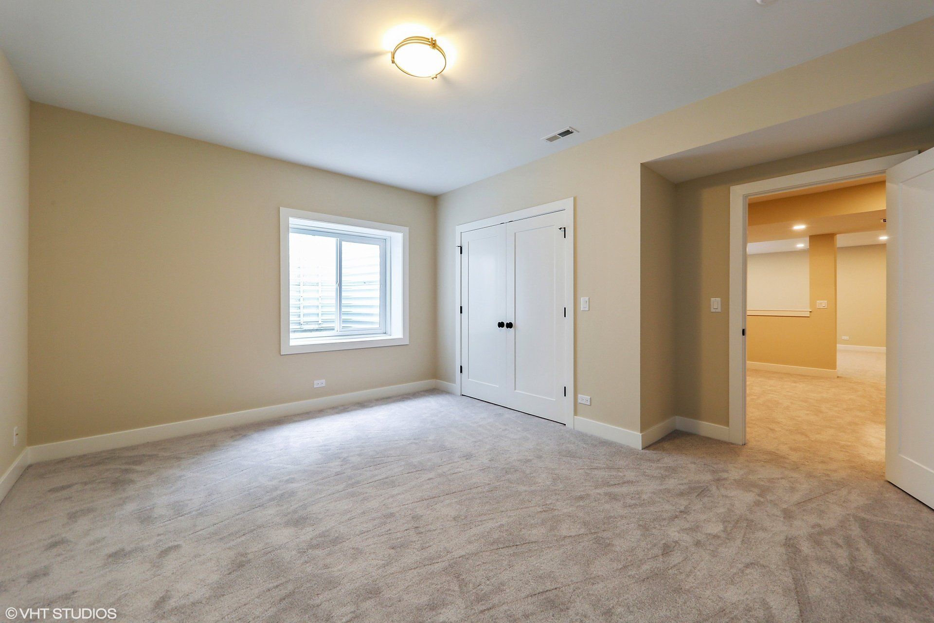 An empty room with a carpeted floor and a window