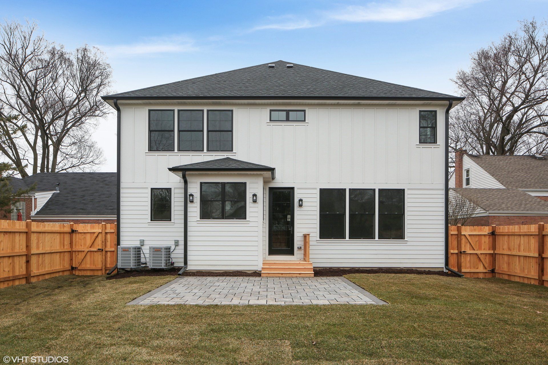 The back of a white house with a wooden fence around it