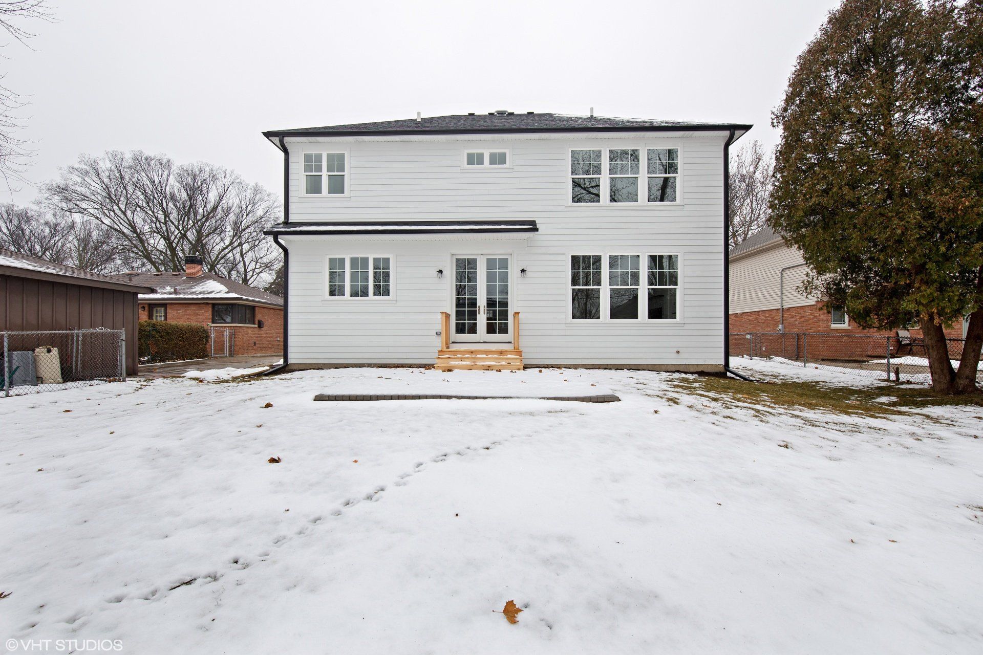 The back of a white house is covered in snow