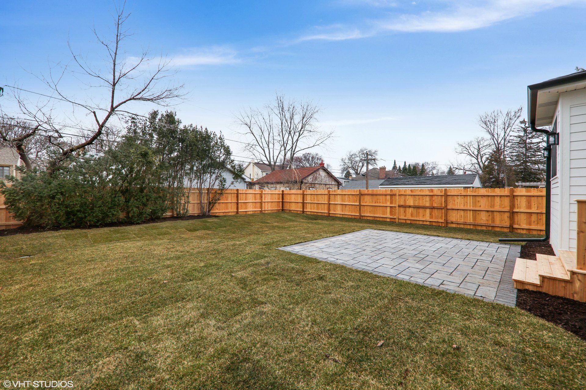 The backyard of a house with a wooden fence and a patio.