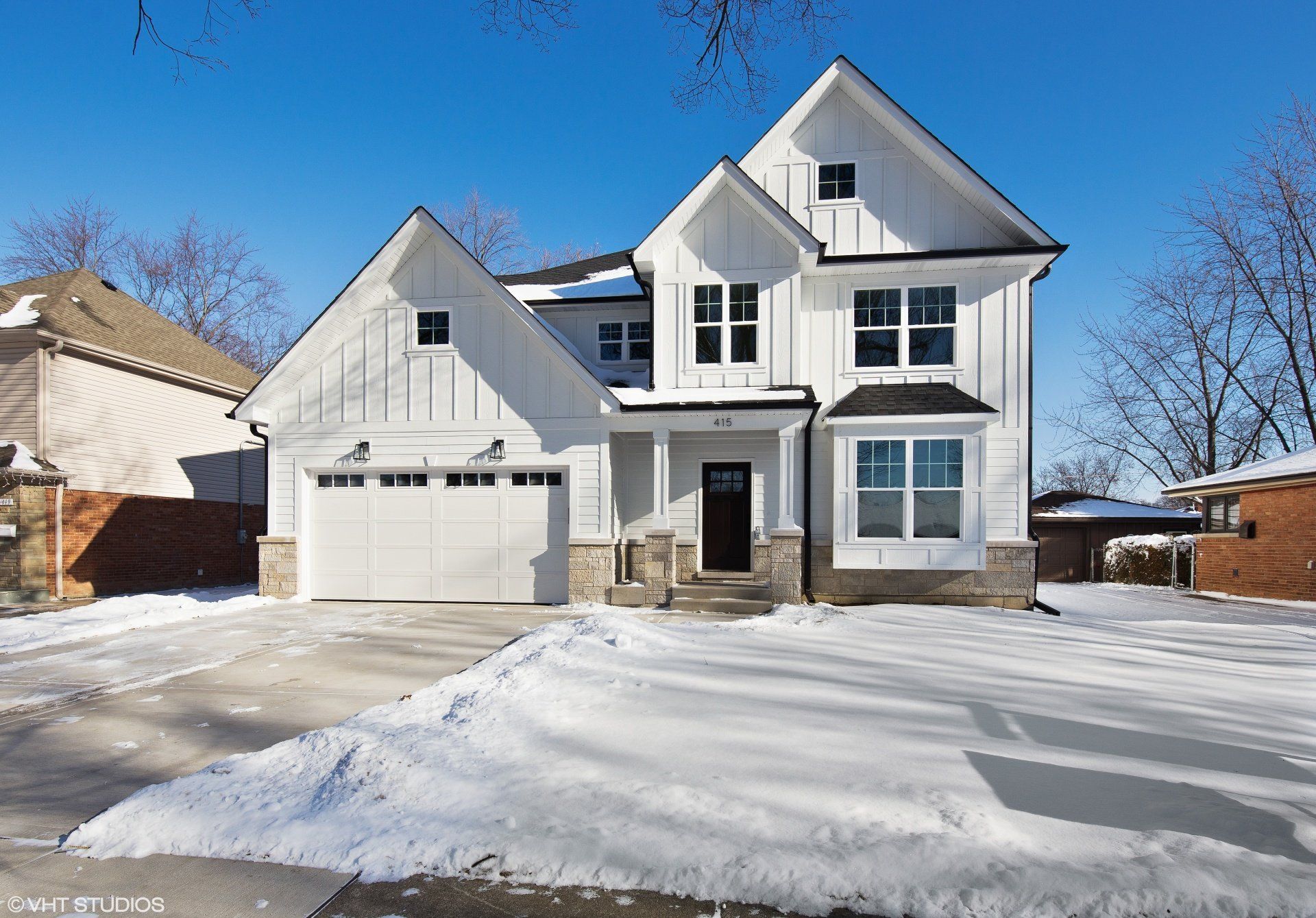 A white house with a garage and a driveway covered in snow.