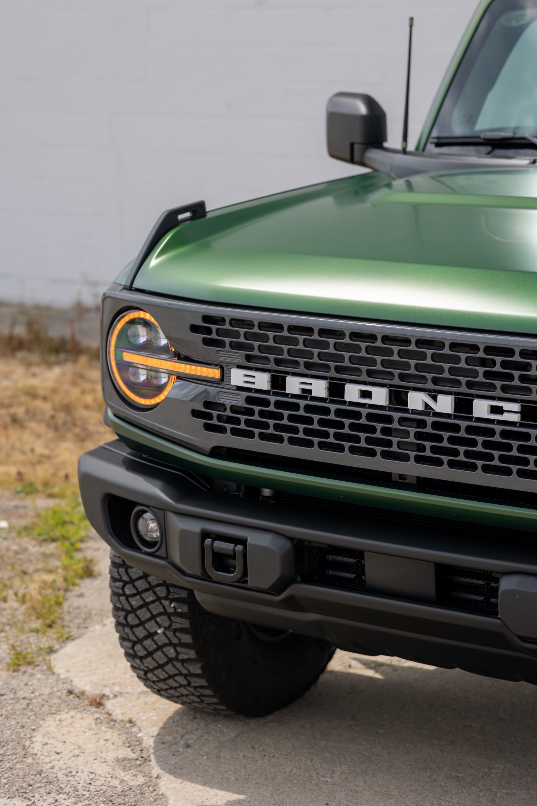 A green ford bronco is parked on the side of the road.