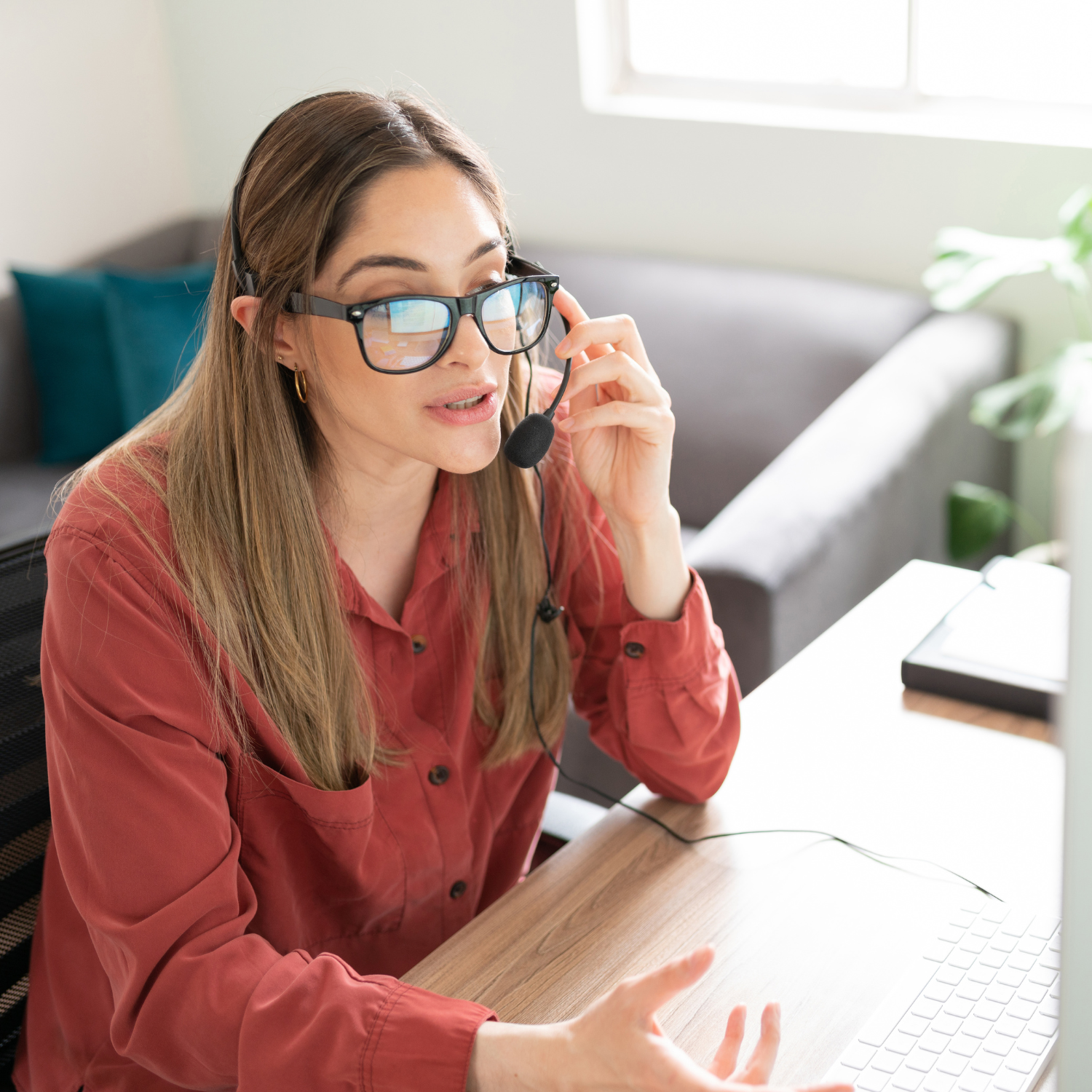 Woman talking in front of the computer, wearing a headset