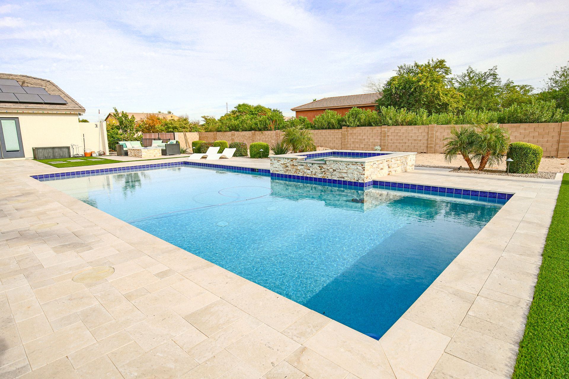 There is a large swimming pool in the backyard of a house.