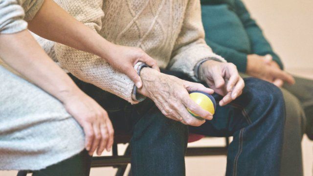 3 people sitting next to eachother holding an older mans hand