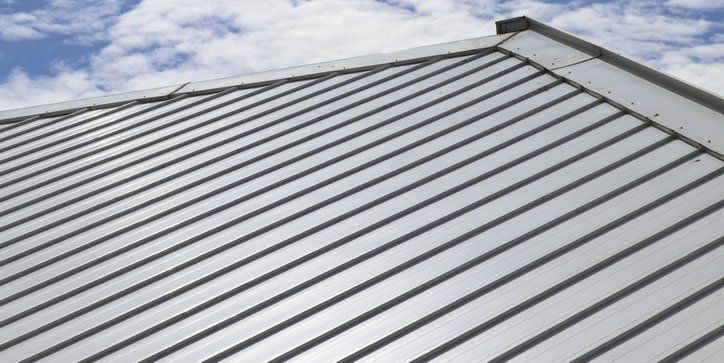 Metal sheet roof and slope with clouds and blue sky background.