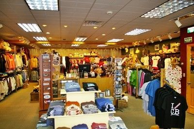 Inside a souvenir shop; clothing racks, shelves of items, and bright overhead lighting.