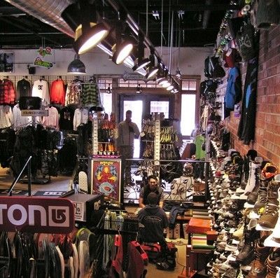 Inside a snowboard shop: snowboards, boots, clothing, and people.