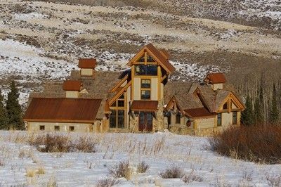 Rustic house in snowy landscape with brown roof and stone walls.