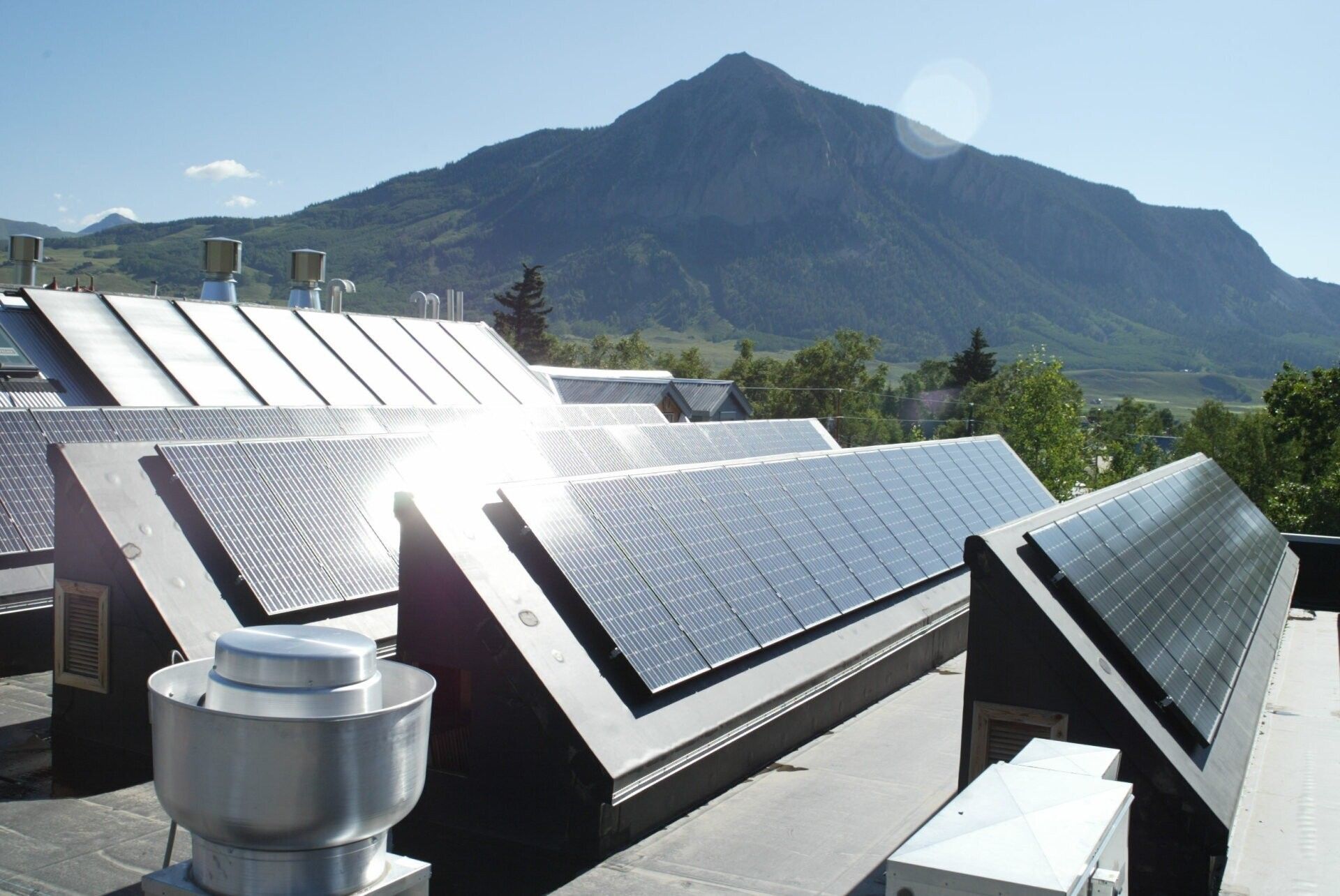 Solar panels on rooftops with a mountain in the background.