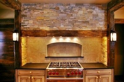 Rustic kitchen with stone backsplash, wooden beams, and stainless steel range.