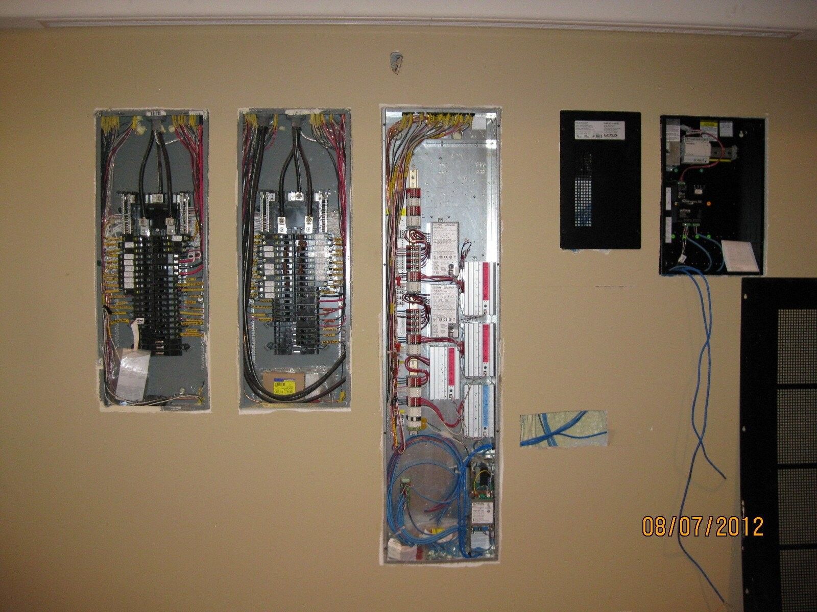 Electrical panels mounted on a beige wall, with wires and components visible.