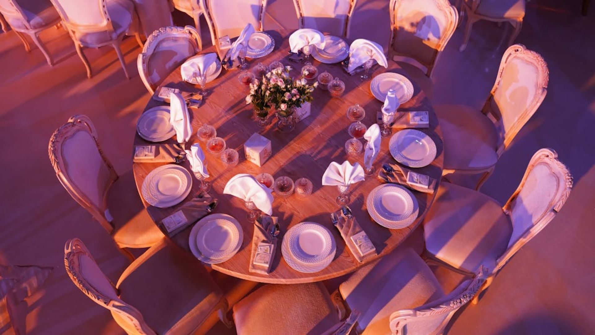 Una mesa redonda para diez personas, puesta con platos blancos, servilletas dobladas 