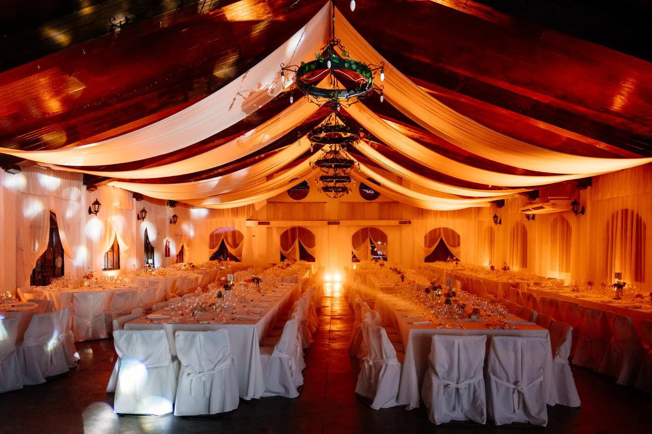 Un salón de banquetes festivo con techos adornados con telas, iluminación cálida 