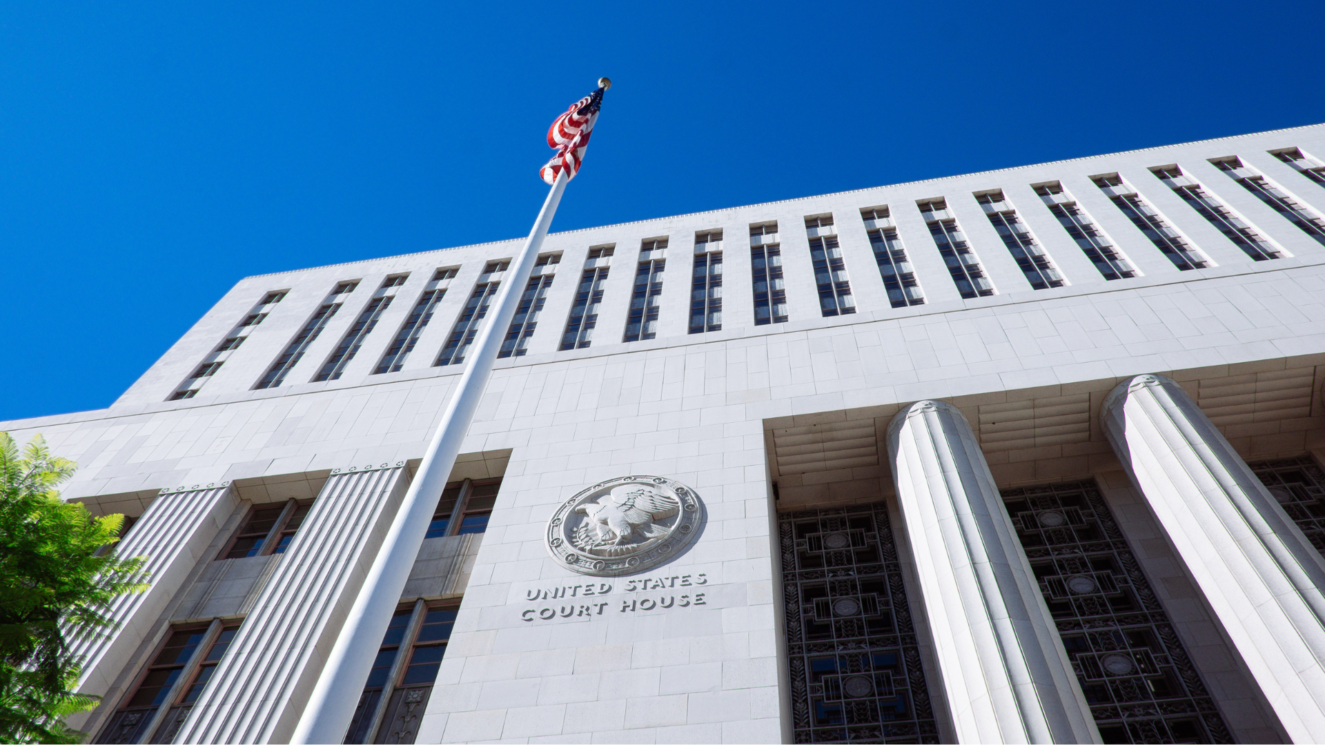 A flag is flying in front of a building that says 