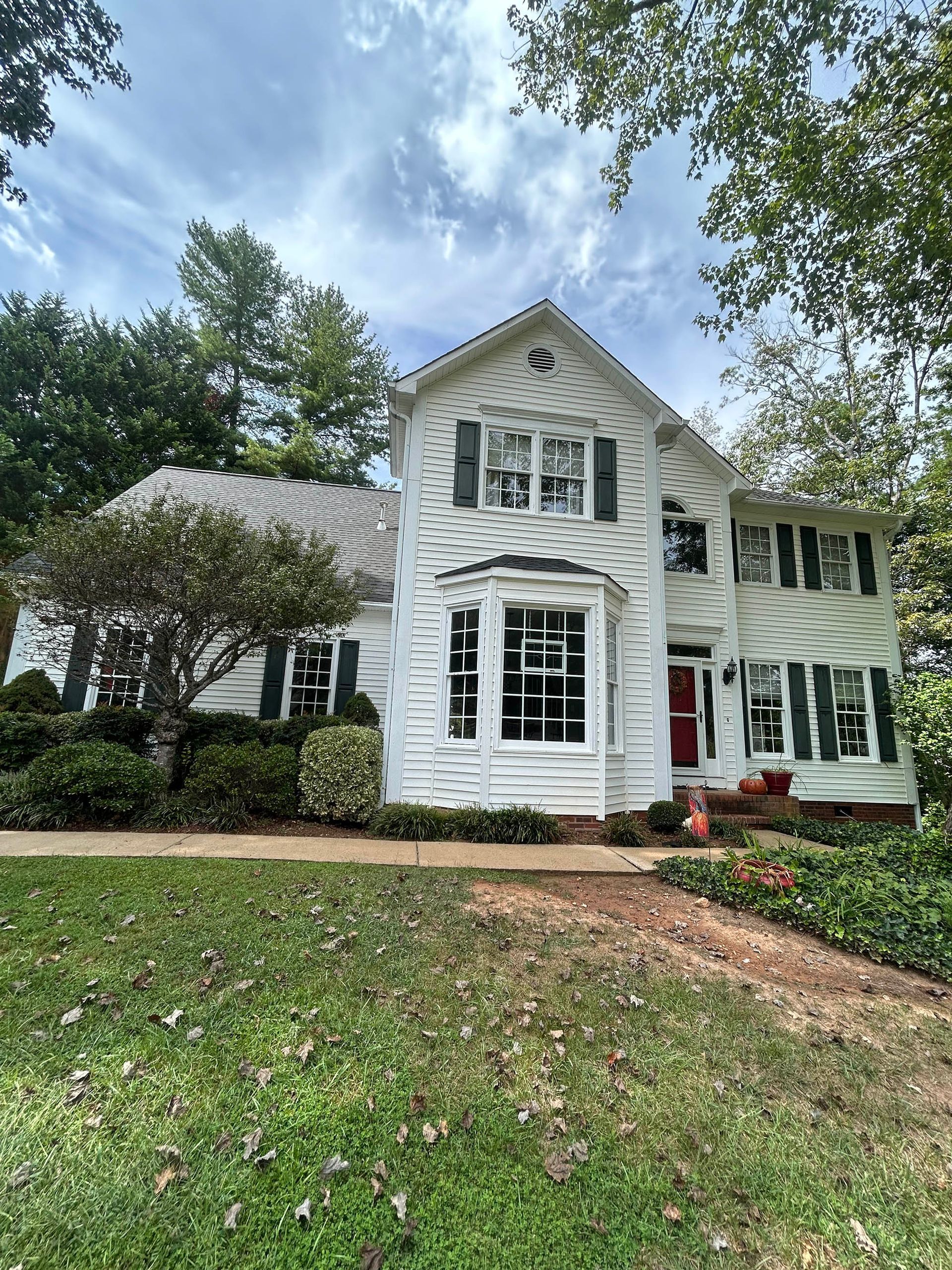 A large white house with a red door is sitting on top of a lush green lawn.