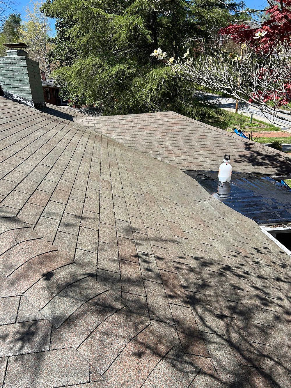 A close up of a roof with a chimney and trees in the background.