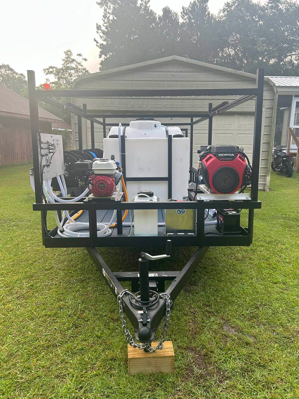 A trailer with a generator attached to it is parked in a grassy yard.