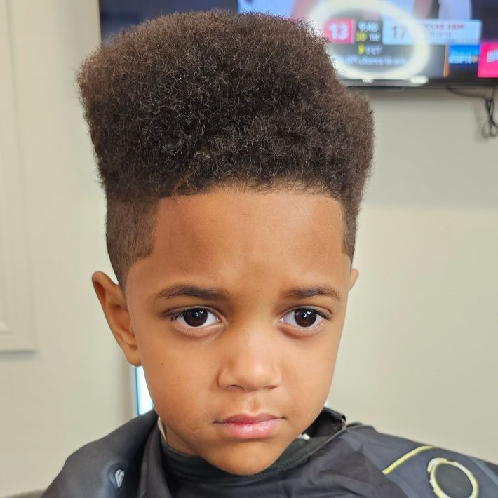 A young boy is getting his hair cut at a barber shop.