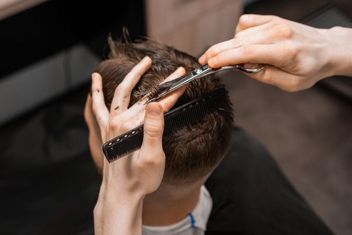 A man is getting his hair cut at a barber shop.