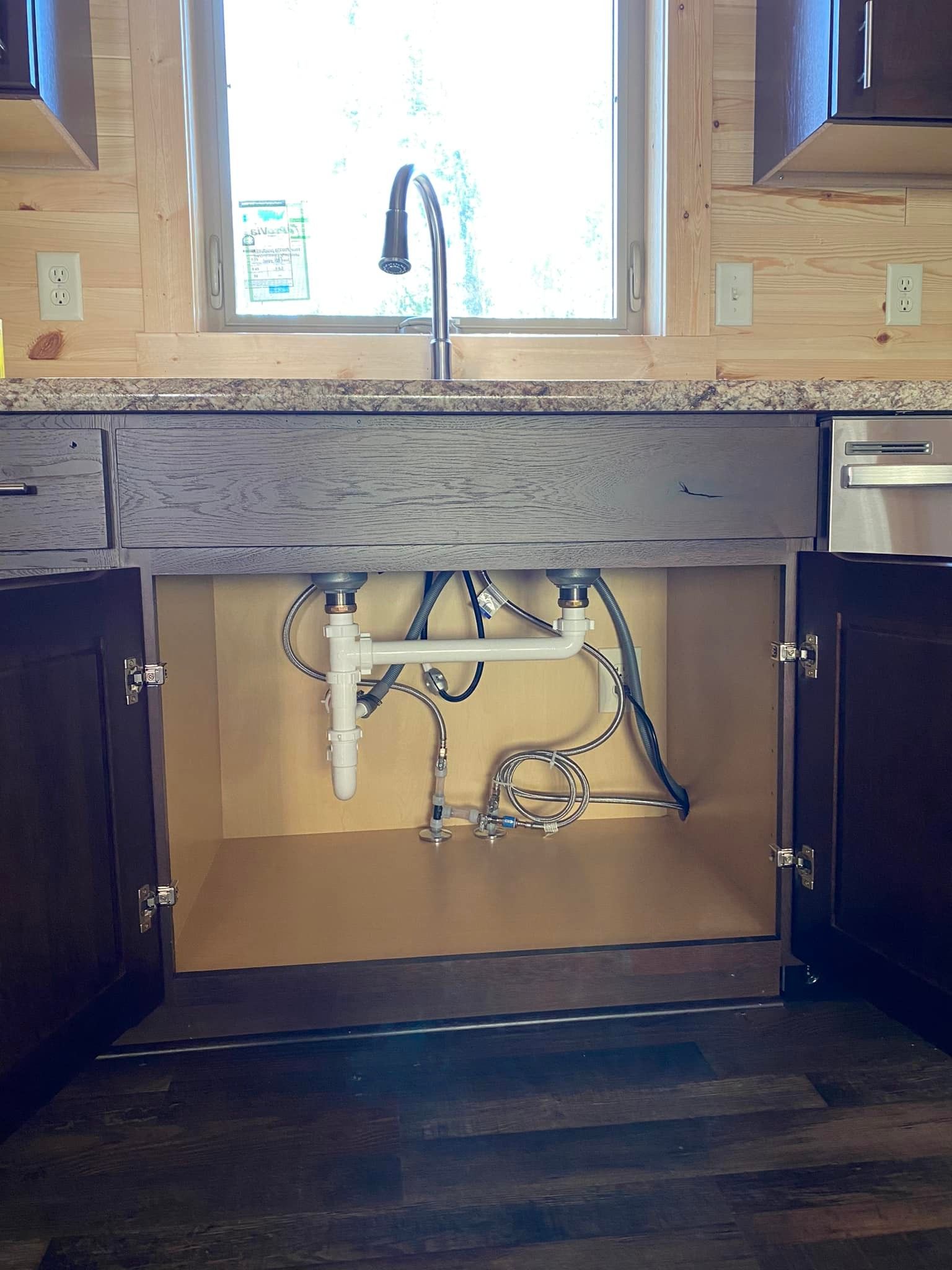 The underside of a kitchen sink with the cabinets open