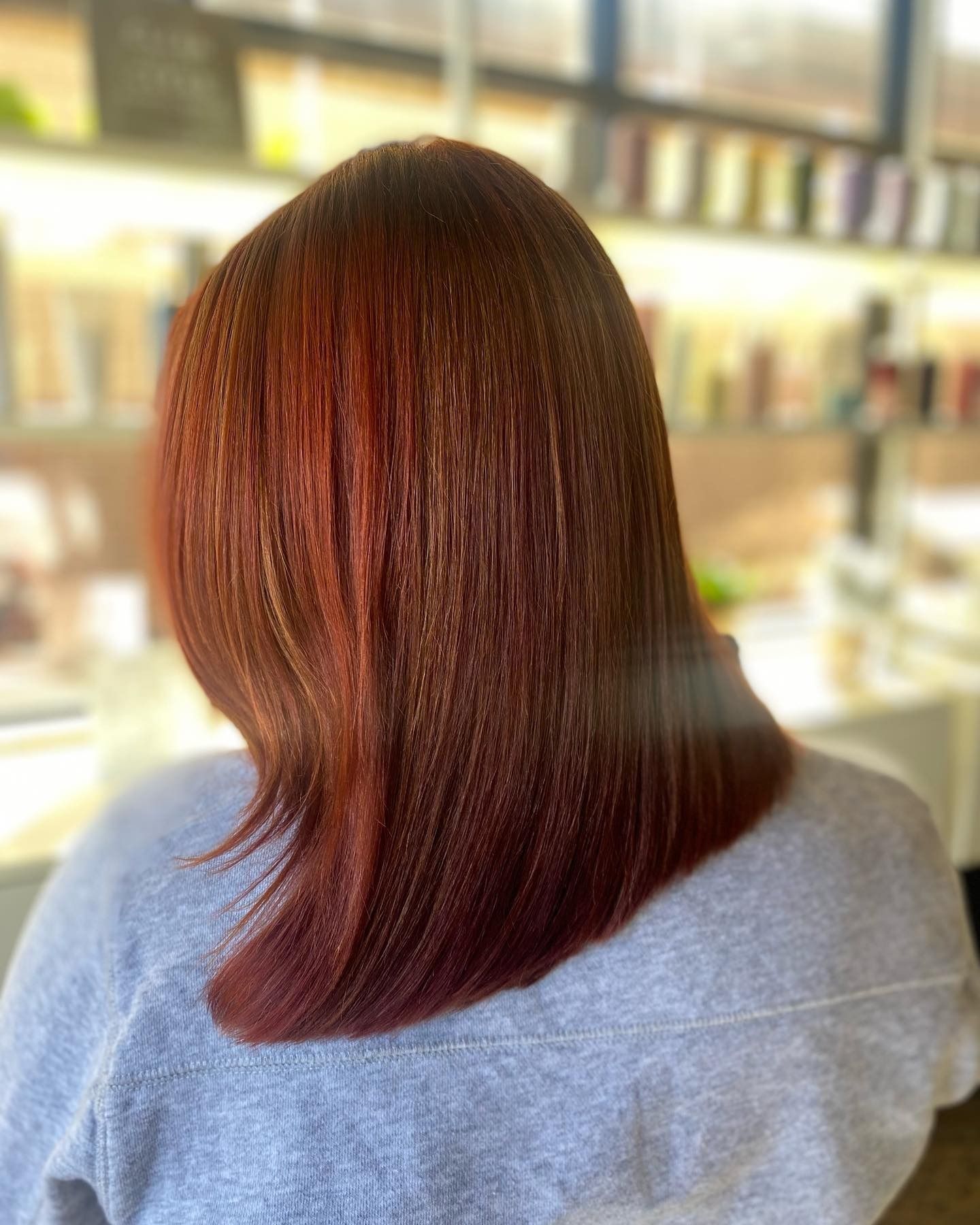 A woman with red hair is sitting in a chair in a salon.
