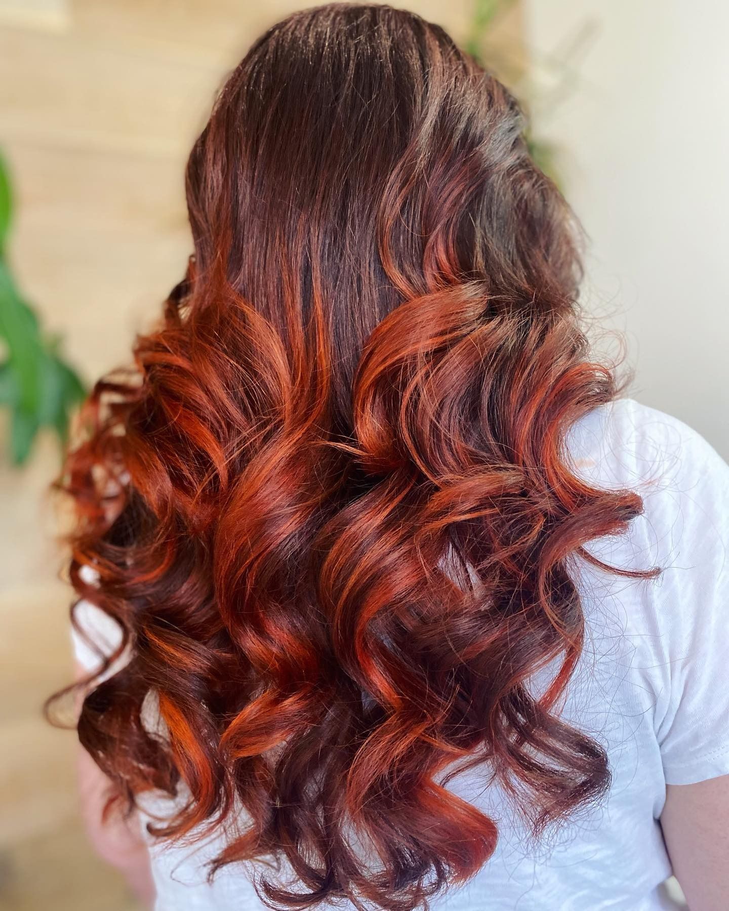 A woman with long red hair is wearing a white shirt.