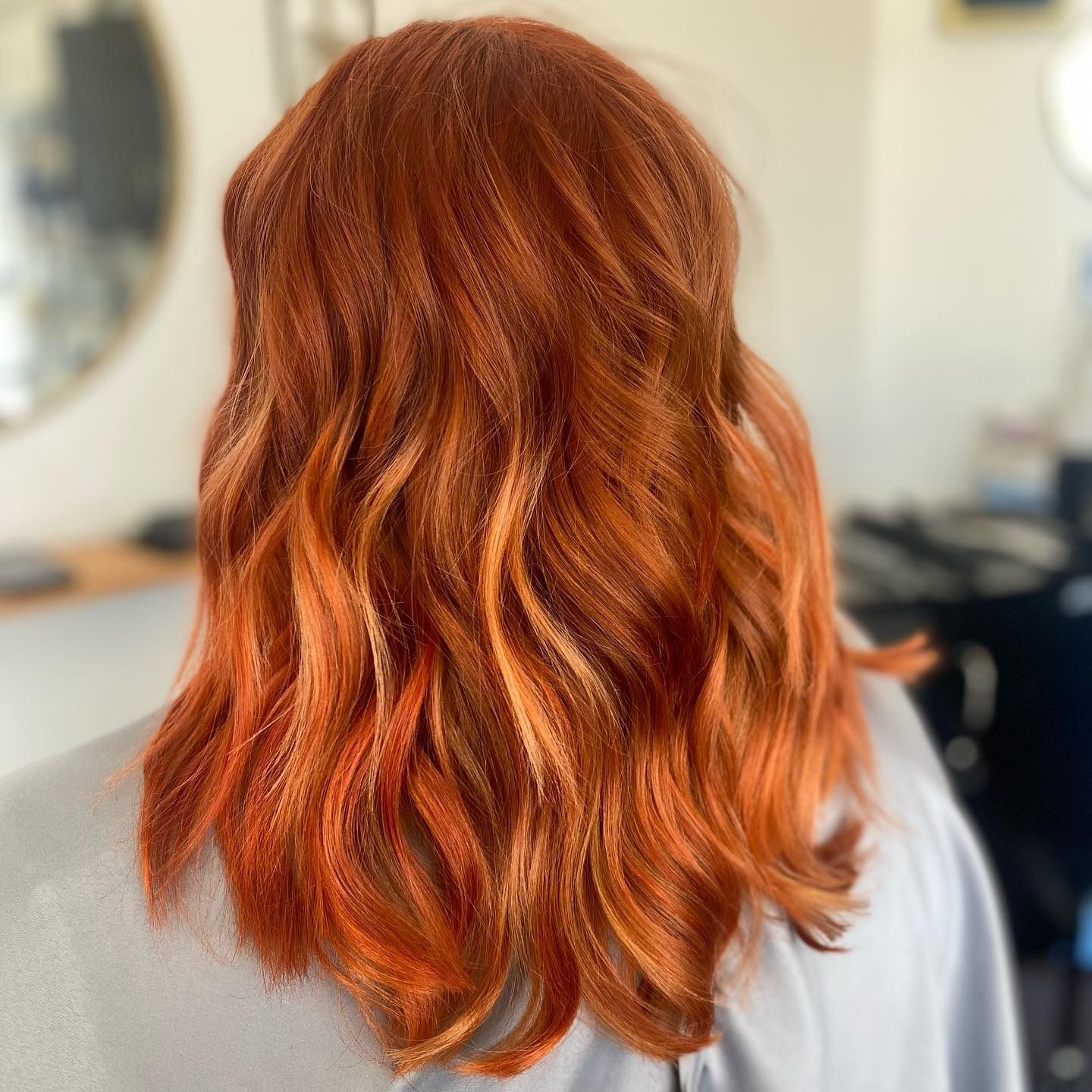 A woman with long red hair is sitting in front of a mirror.