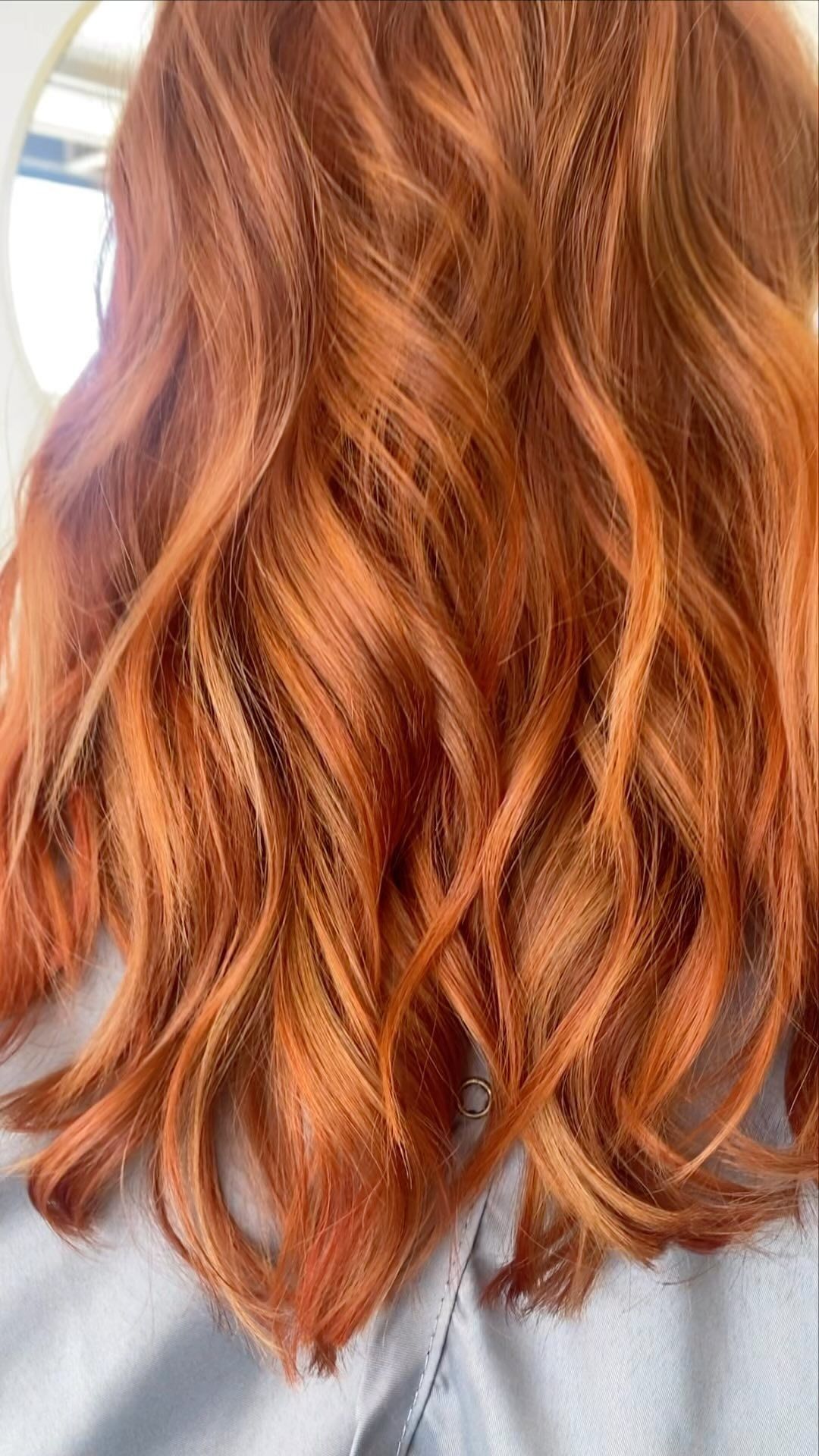 A woman with red hair is sitting in front of a mirror.