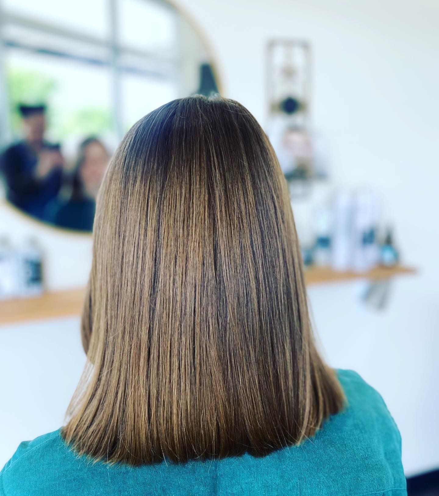 The back of a woman 's head is shown in front of a mirror.