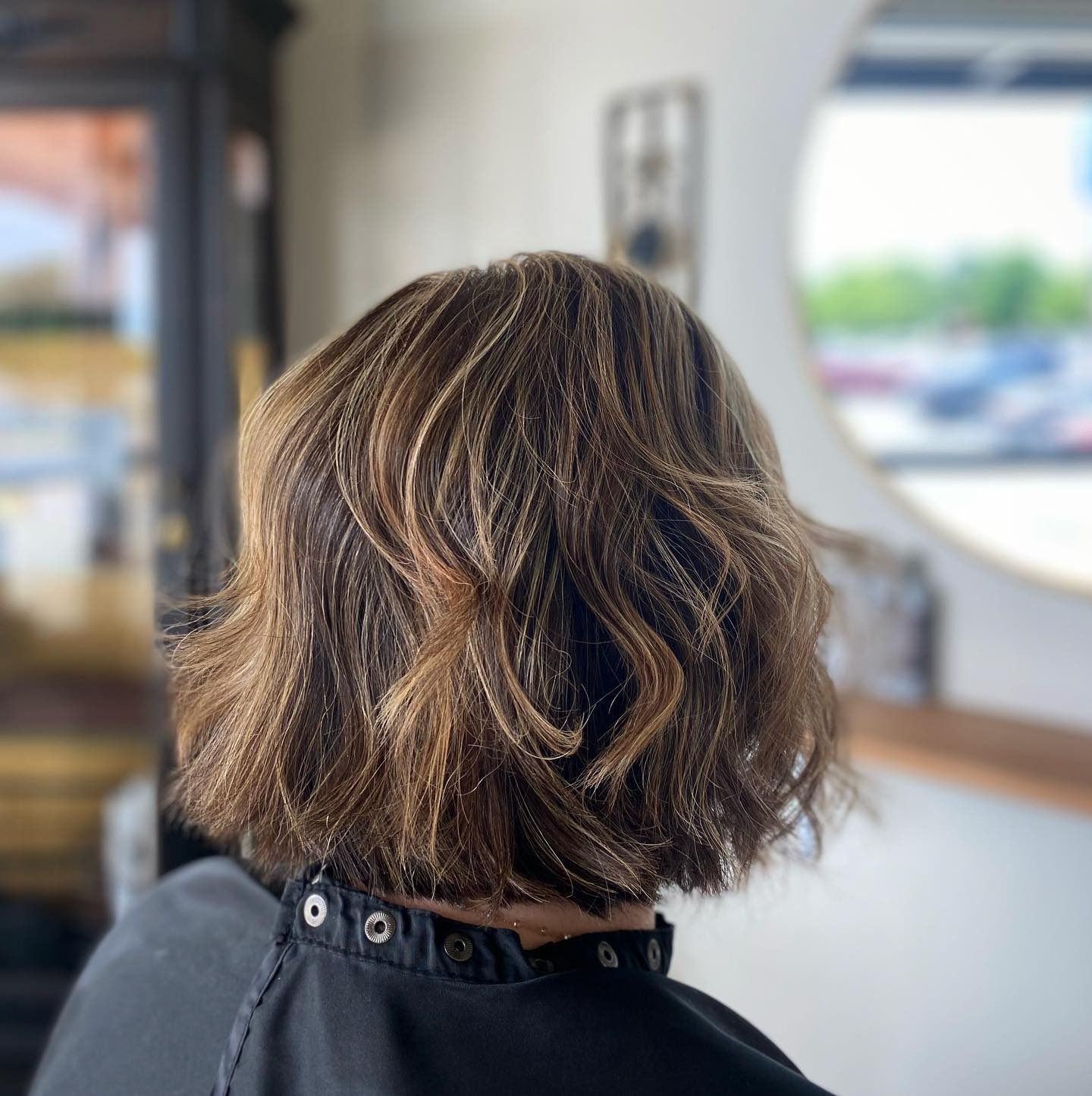 A woman with short brown hair is wearing a black cape