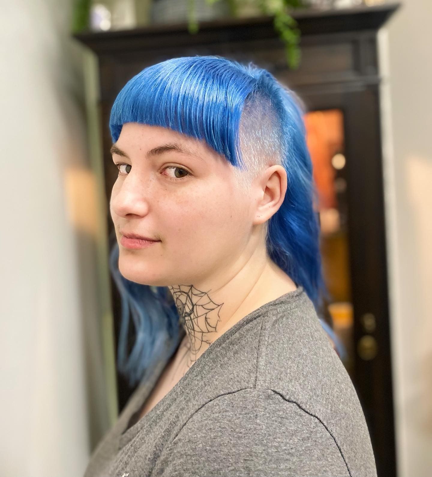 A woman with blue hair and a tattoo on her neck