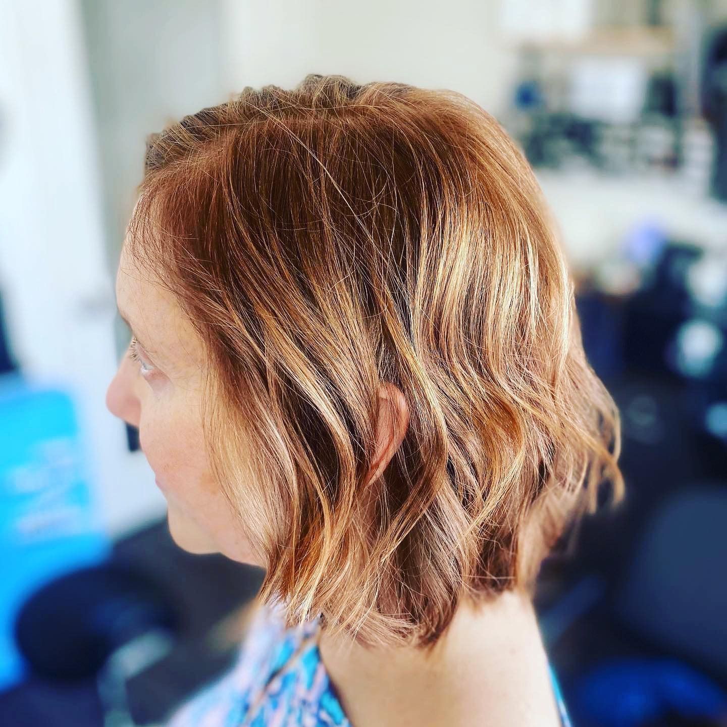 A woman with short red hair is sitting in a chair.